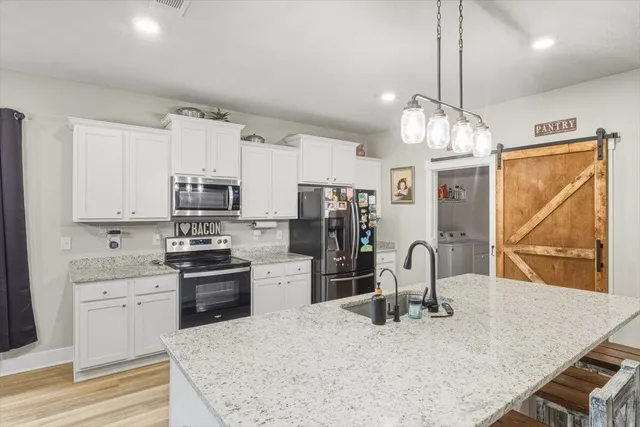 a kitchen with stainless steel appliances granite countertop a sink dishwasher and a refrigerator with wooden floor