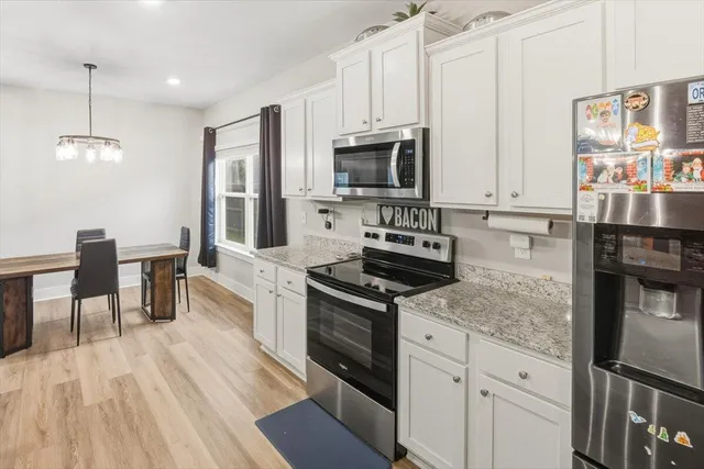 a kitchen with stainless steel appliances granite countertop a stove top oven a sink dishwasher a microwave oven and a dining table with wooden floor
