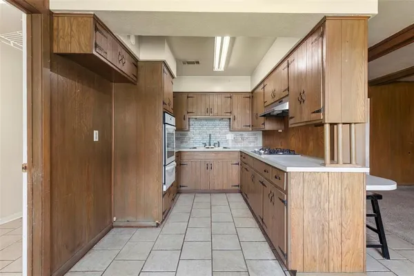 a large kitchen with stainless steel appliances kitchen island granite countertop a refrigerator a sink dishwasher a stove and white countertops with cabinets