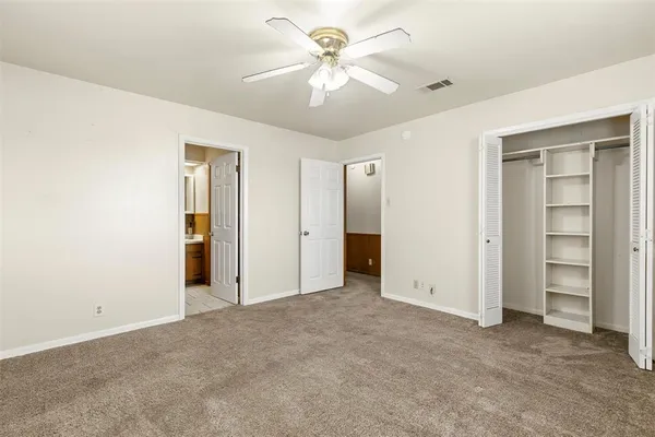 an empty room with closet and a ceiling fan