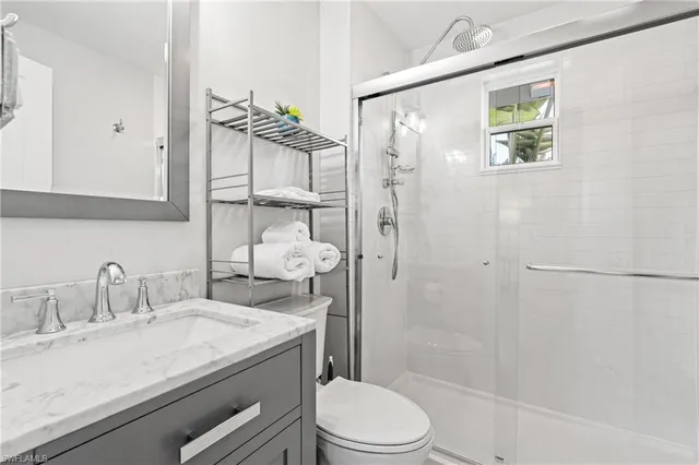 a bathroom with a granite countertop sink a toilet and shower