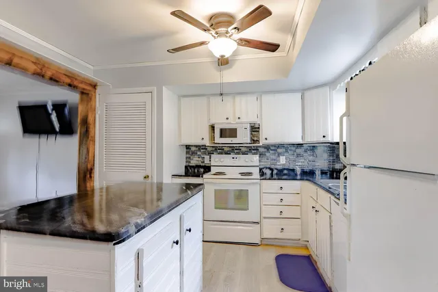 a kitchen with granite countertop a sink stainless steel appliances and white cabinets