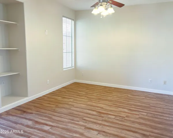 a view of an empty room with wooden floor and a window