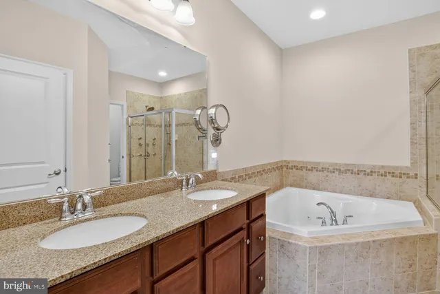 a bathroom with a granite countertop sink a bathtub and a mirror
