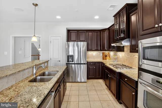 a kitchen with stainless steel appliances granite countertop a sink refrigerator and cabinets