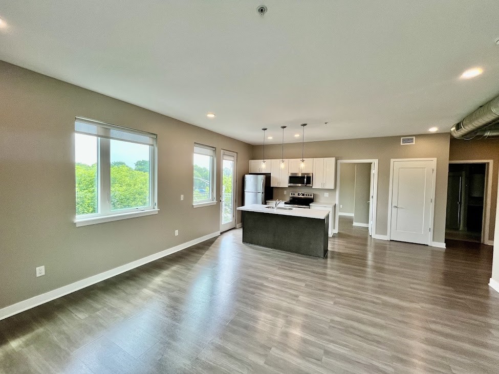 625 South Goodman Street, Unit 311 Rochester, NY 14620 - Photo 4 of 23 View of great room with views of Rochester city skyline out the windows and showing doorway to bedroom 2 as well asdoor to balcony
