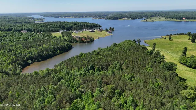 an aerial view of a houses with a yard and lake view