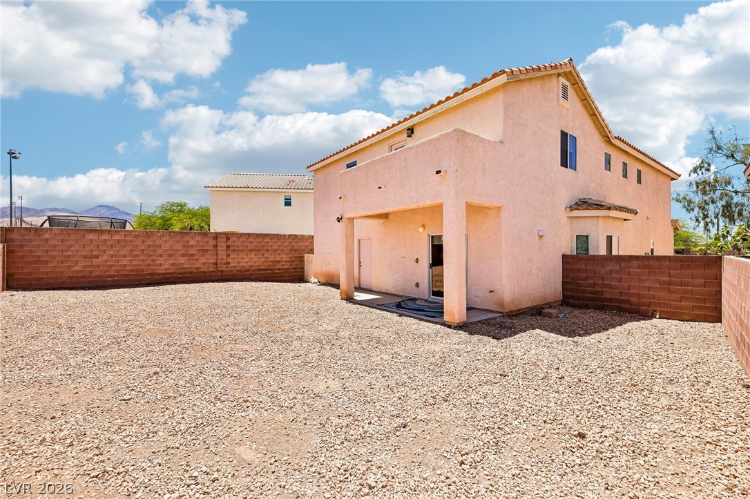 1176 Butternut Ranch Court Henderson, NV 89052 - Photo 41 of 60 A spacious backyard with a covered patio offers ample outdoor living potential, framed by block fencing and distant mountains.