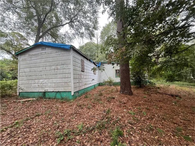 a backyard of a house with plants and large tree