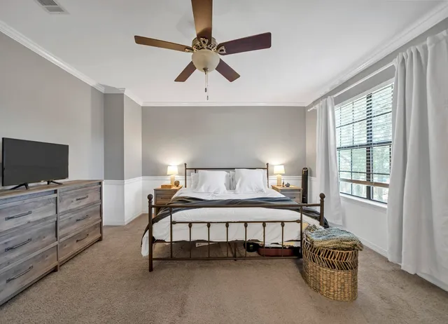 a spacious bedroom with a bed and a flat tv screen on dresser