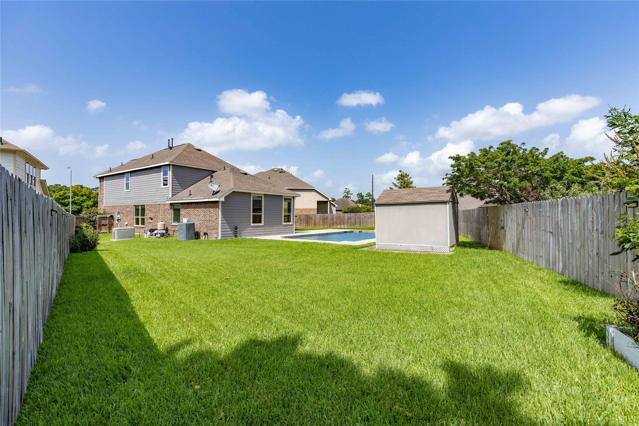 17206 Upper Ridge Lane Humble, TX 77346 - Photo 46 of 50 Spacious backyard featuring a well-maintained lawn, a storage shed, and a swimming pool, all enclosed by a wooden fence for privacy. Ideal for outdoor activities and relaxation.