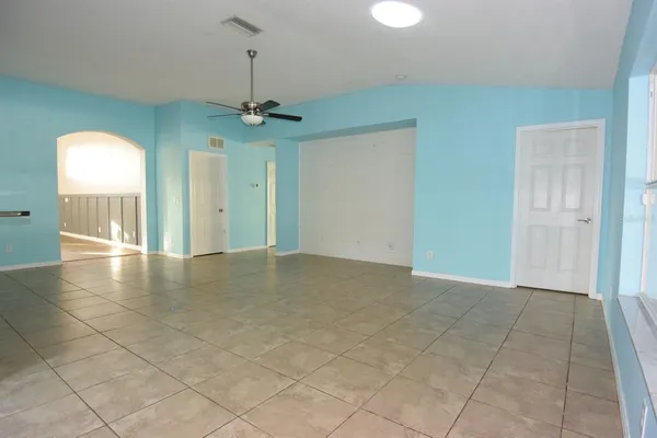an empty room with a chandelier fan and windows