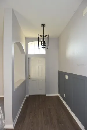 an empty room with chandelier fan and windows