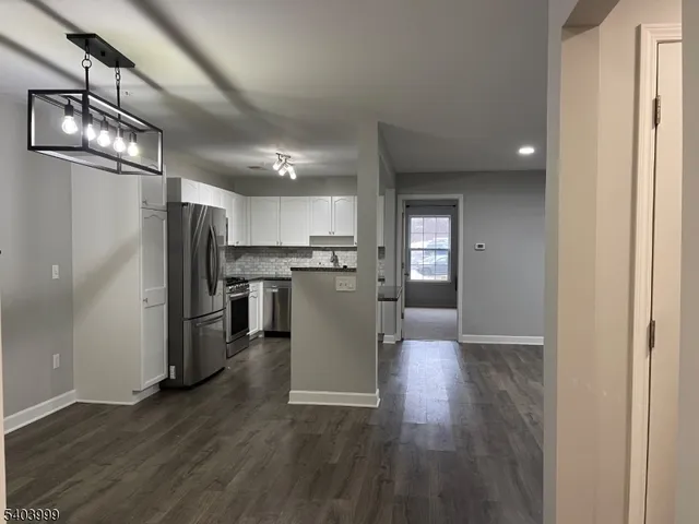 a view of a kitchen with a refrigerator and wooden floor