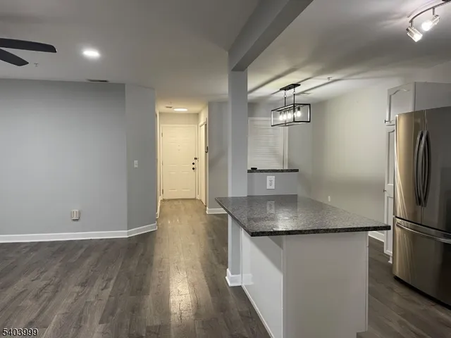 an empty room with wooden floor and a refrigerator