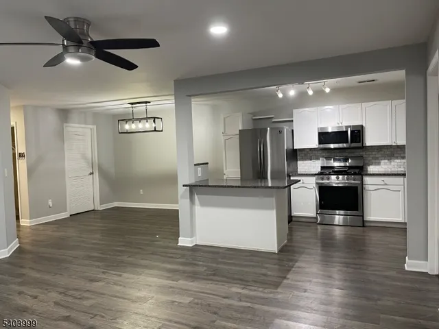 a kitchen with granite countertop a refrigerator and a stove top oven
