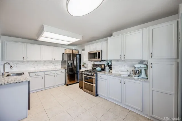 a kitchen with a sink white cabinets and stainless steel appliances