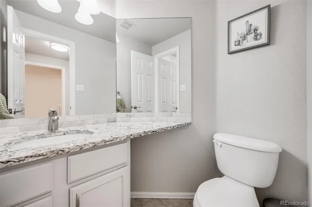 a bathroom with a granite countertop toilet sink and mirror