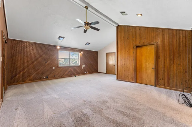 an empty room with windows and fan