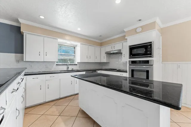 a kitchen with granite countertop white cabinets and stainless steel appliances