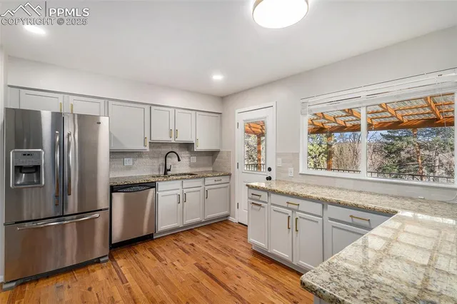 a kitchen with granite countertop stainless steel appliances a sink cabinets and a large window