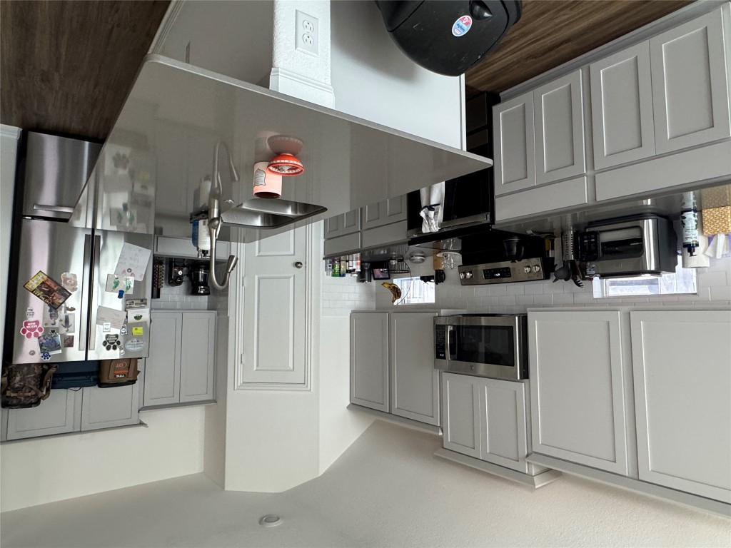 2005 Long Shadow Lane Georgetown, TX 78628 - Photo 16 of 21 Kitchen featuring range, stainless steel fridge, gray cabinets, decorative backsplash, and dark wood-style flooring