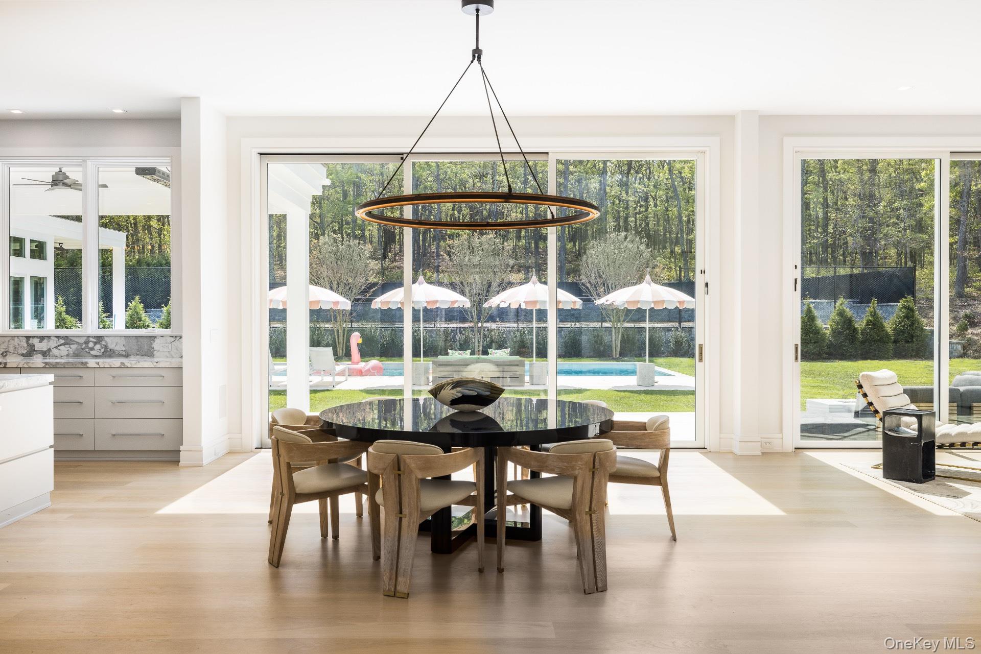 1552 Deerfield Road Water Mill, NY 11976 - Photo 14 of 37 a dining room with wooden floor glass table and chairs