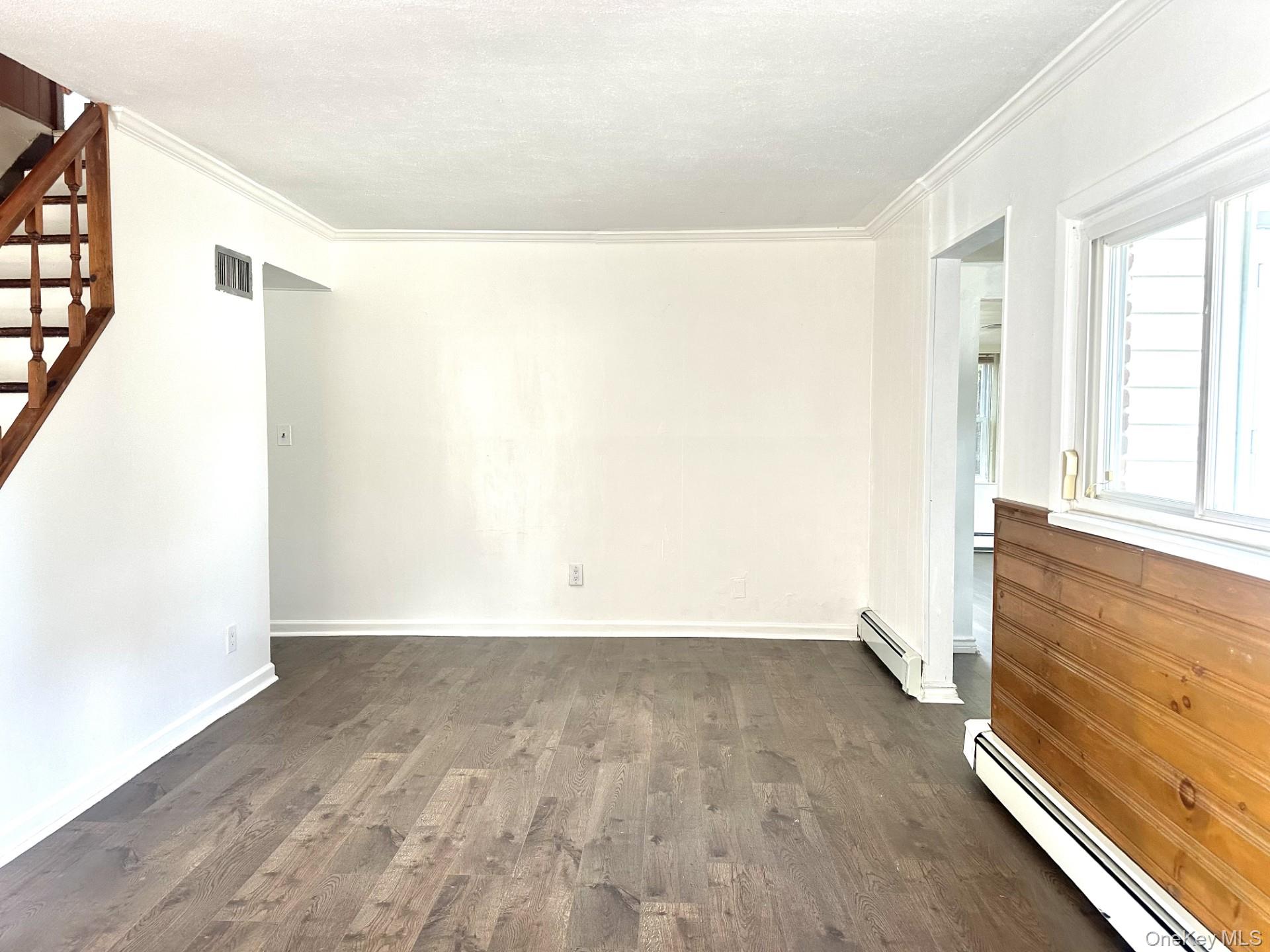 27 Collins Road Glen Cove, NY 11542 - Photo 8 of 13 an empty room with wooden floor and windows with curtains