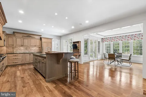 a living room with stainless steel appliances granite countertop furniture wooden floor and a large window