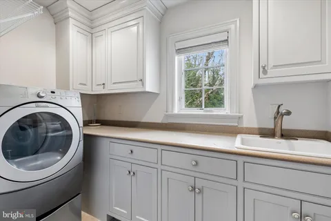 a close view of a sink and dishwasher with white cabinets
