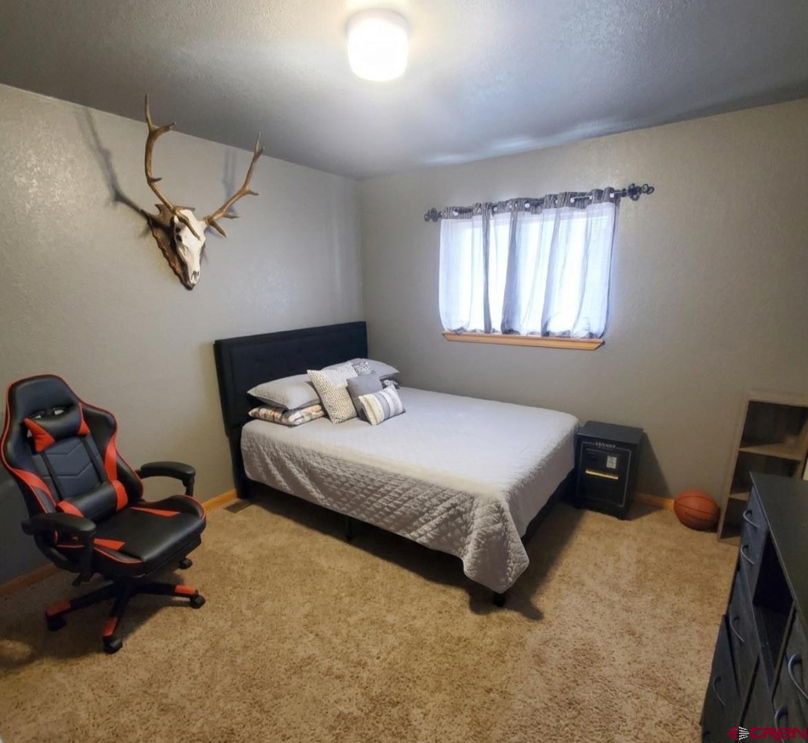 816 Main Street Manassa, CO 81141 - Photo 13 of 23 a bedroom with a bed and a chandelier