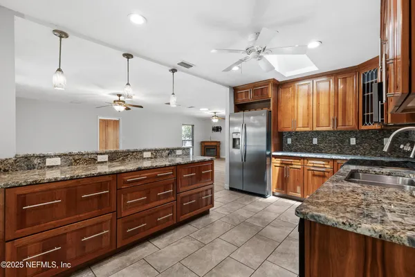 a large kitchen with granite countertop a sink a counter top space appliances and cabinets