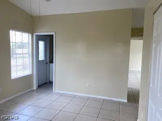 a view of an empty room with window and chandelier fan