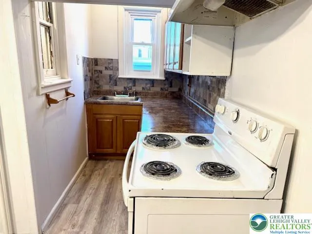 a kitchen with a stove cabinets and wooden floor