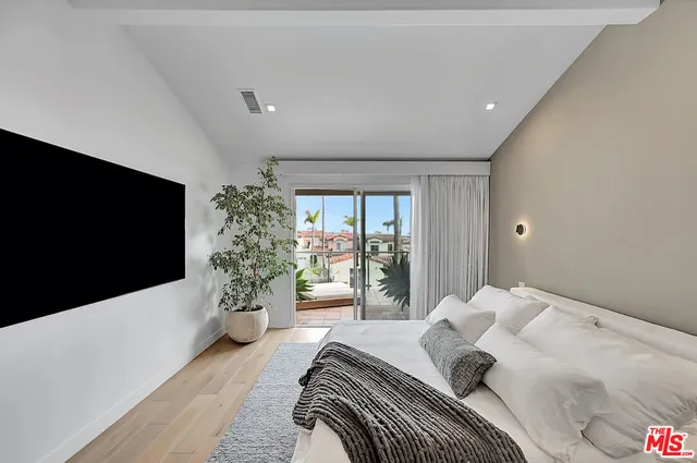 a bedroom with a potted plant on a bed and a flat screen tv