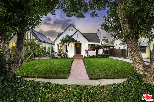 a front view of a house with a yard and fountain