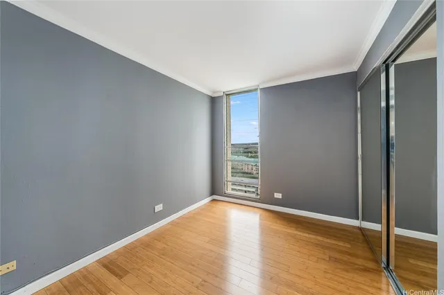 a view of an empty room with wooden floor and a window