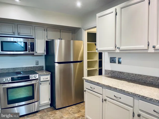 a kitchen with granite countertop white cabinets and stainless steel appliances