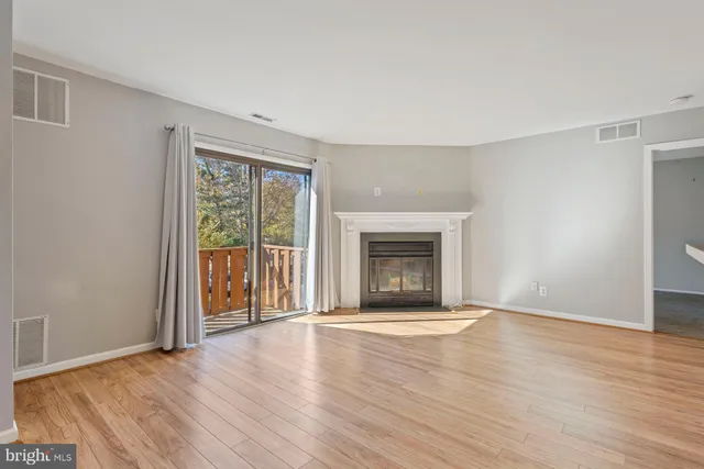 an empty room with wooden floor fireplace and windows