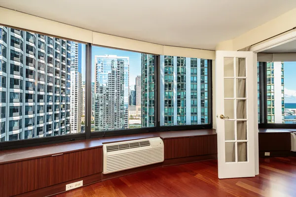 a view of an empty room with wooden floor and a window