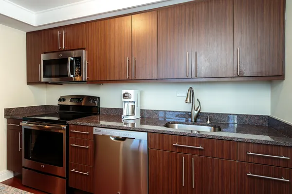 a kitchen with granite countertop wood cabinets stainless steel appliances and a sink