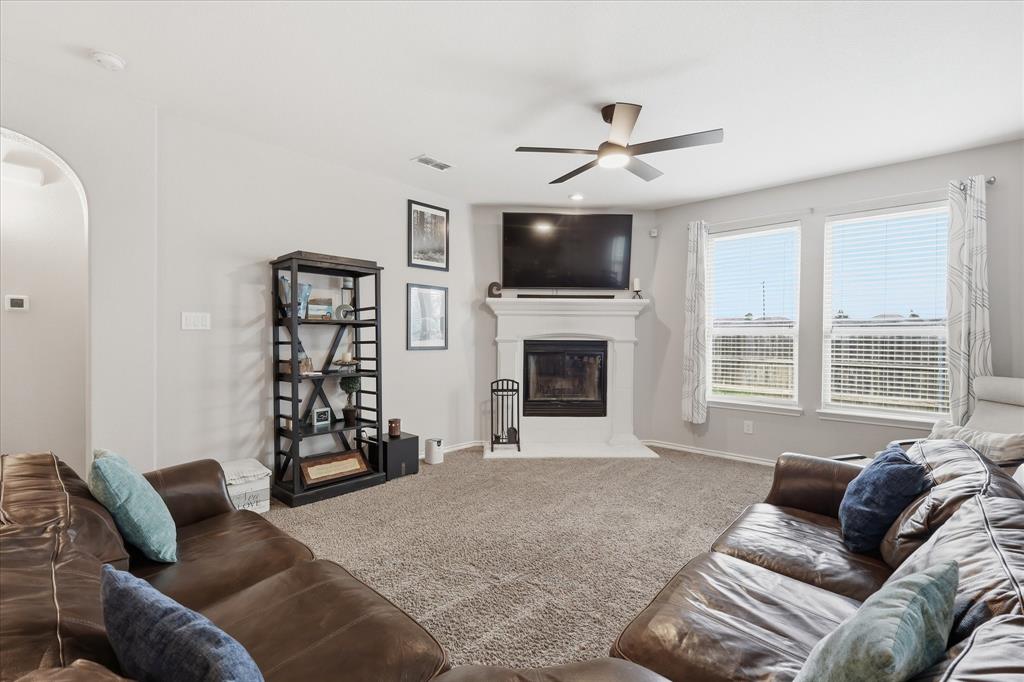 11500 Starlight Ranch Fort Worth, TX 76052 - Photo 10 of 40 Living area featuring a fireplace with a mantel, two windows with blinds, a ceiling fan, and carpeted flooring