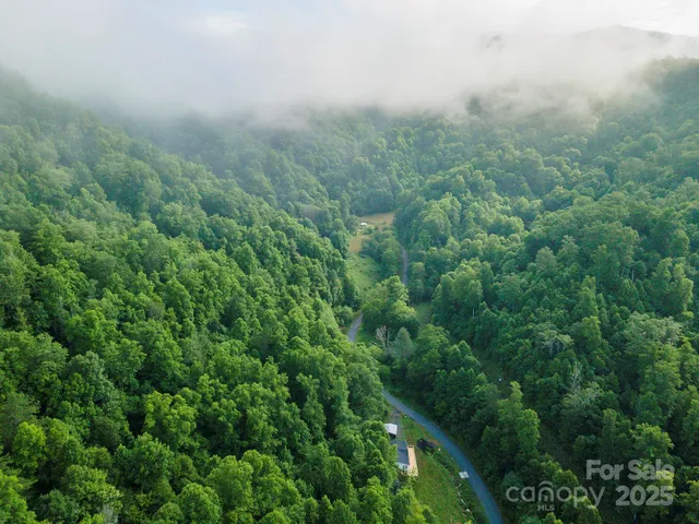 an aerial view of residential house with outdoor space and trees all around
