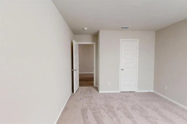 a view of an empty room with glass door and fan
