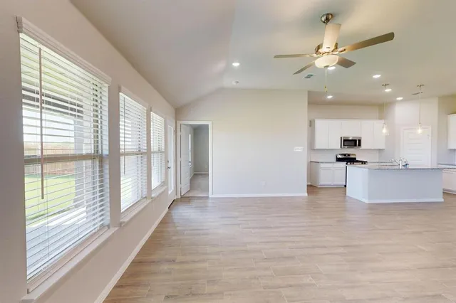 a view of an empty room with a window and wooden floor