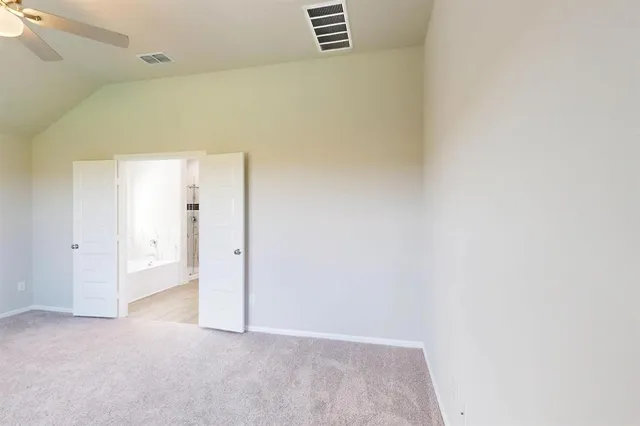 an empty room with chandelier fan and windows
