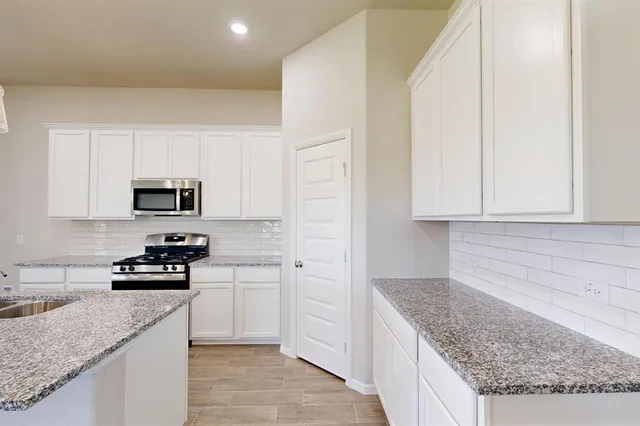 a kitchen with granite countertop a sink a stove and cabinets