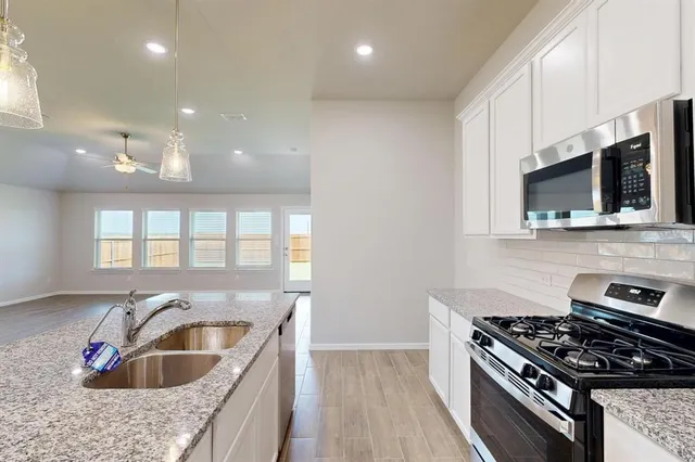 a kitchen with granite countertop a sink and a stove top oven