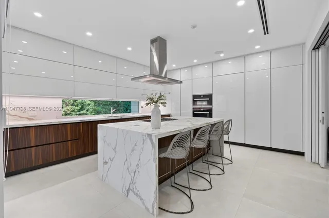 a kitchen with stainless steel appliances kitchen island granite countertop a table chairs in it and wooden floors