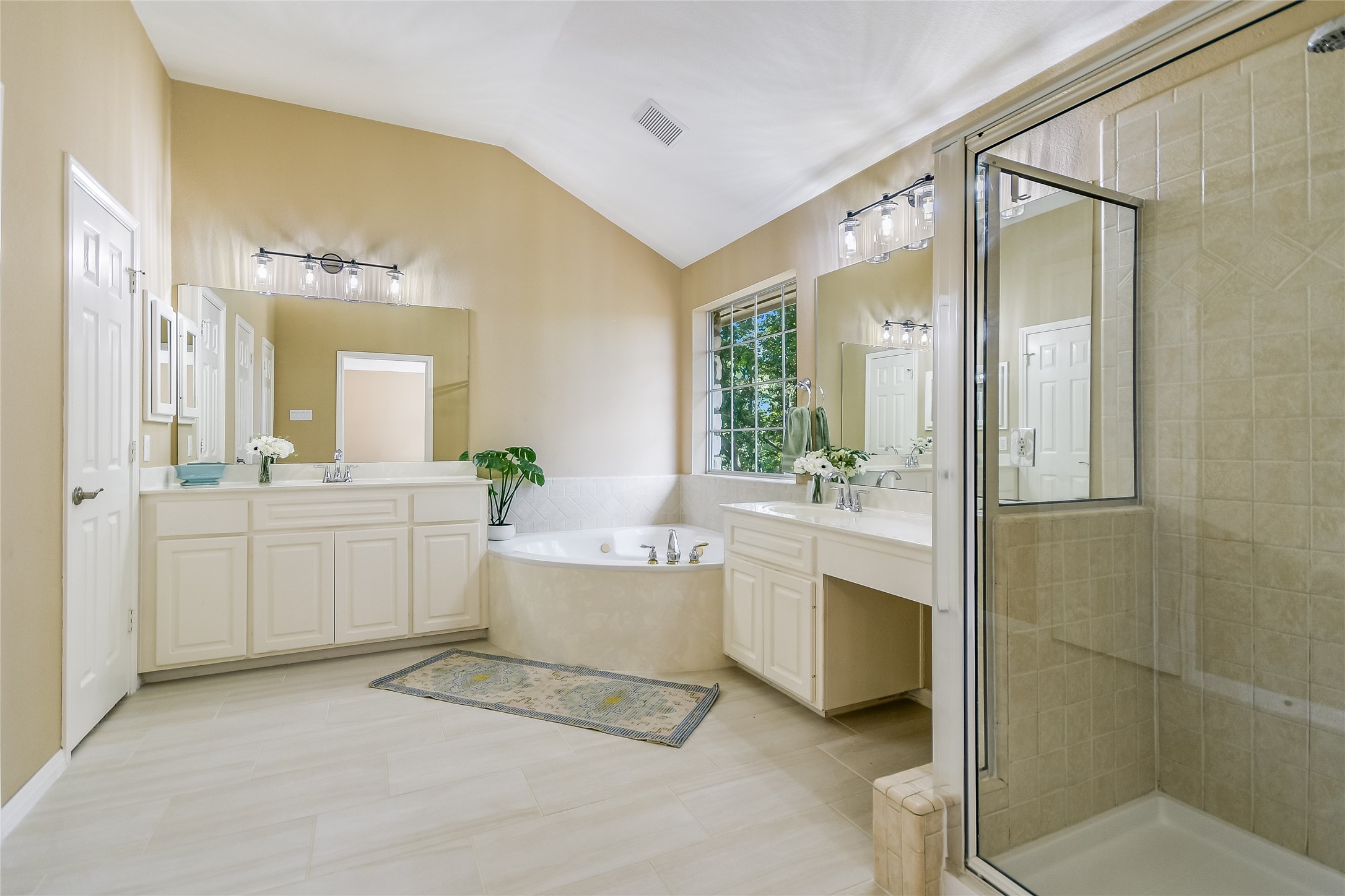 12935 Brigham Drive Austin, TX 78732 - Photo 21 of 35 Primary Bathroom - This ensuite primary bath has new tile flooring, a double vanity, garden tub, separate shower, and new sink faucets and vanity light fixtures.